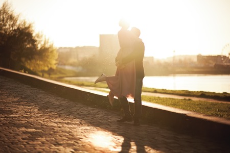 Wedding couple, groom and dress posing near river with a glass at sunset.の写真素材