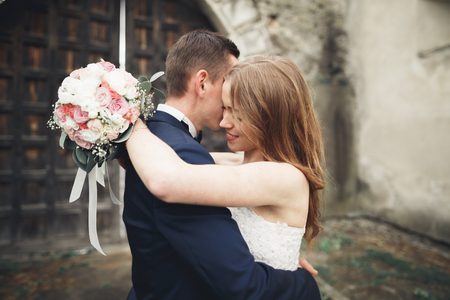 Beautiful romantic wedding couple of newlyweds hugging near old castle.の写真素材