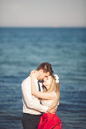 Young happy couple walking on beach smiling holding around each other. Love story.の写真素材