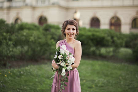Beautiful bride, girl outdoors posing with bouquet.の写真素材