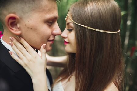 Beautiful young wedding couple is kissing and smiling in the park.の写真素材