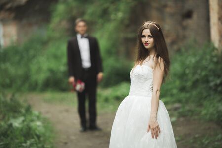 Closeup portrait of beautiful bride with wedding bouquet isolated at green natural summer field...