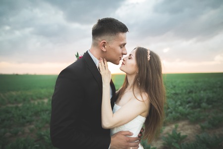 Beautiful couple in field, Lovers or newlywed posing on sunset with perfect sky.