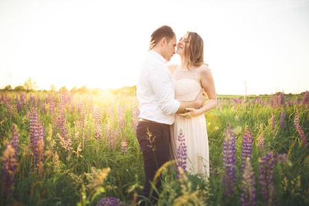 Beautiful couple, bride, groom kissing and hugging in the field sunset.