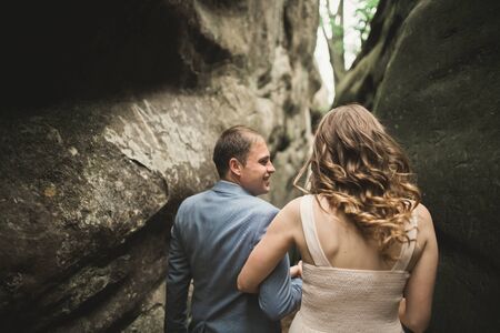 Gorgeous wedding couple kissing and hugging in forest with big rocks.の写真素材