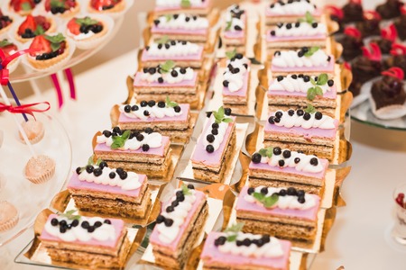 Delicious and tasty dessert table with cupcakes and shots at reception closeup.
