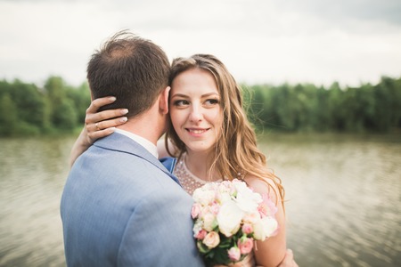Bride and groom holding beautiful wedding bouquet. Lake and forest.の写真素材