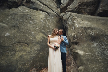 Happy wedding couple kissing and hugging near a high cliff.の写真素材
