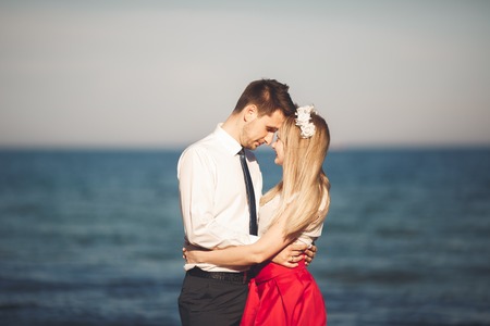 Young happy couple walking on beach smiling holding around each other. Love story.の写真素材