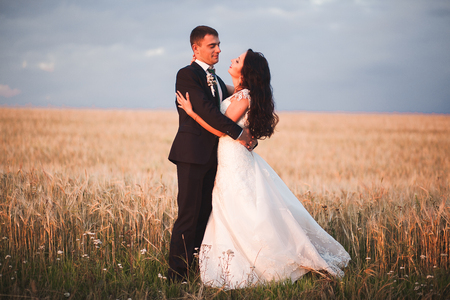 Beautiful romantic wedding couple of newlyweds hugging in park on sunset.の写真素材