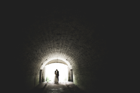 Beautiful fairytale newlywed couple hugging near old medieval castle.の写真素材