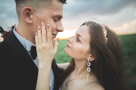 Wedding, Beautiful Romantic Bride and Groom Kissing and Embracing at Sunset.の写真素材