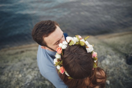 Wedding couple kissing and hugging on rocks near blue sea.の写真素材