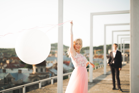 Pretty sunny outdoor portrait of young stylish couple while kissing on the roof with city view.の写真素材