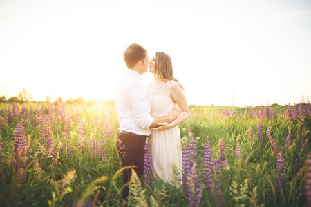 Young wedding couple walking on field with flowers.の写真素材