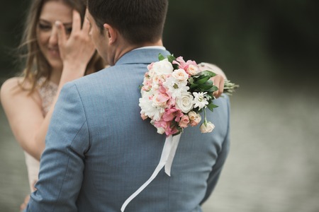 Elegant beautiful wedding couple posing near a lake at sunset.の写真素材