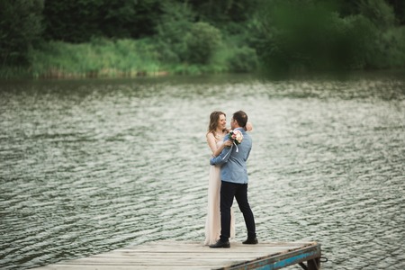 Elegant beautiful wedding couple posing near a lake at sunset.の写真素材