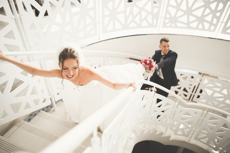 Lovely happy wedding couple, bride with long white dress posing in beautiful city.の写真素材