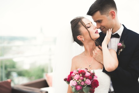 Beautiful couple, bride and groom posing on balcony with backgrounf of old city.の写真素材