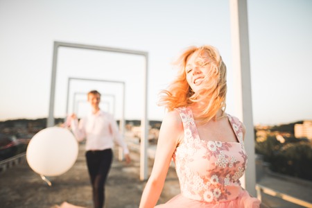 Fashion lovely beautiful couple posing on roof with city background. Young man and sensual blonde outdoor. Lifestyle..の写真素材