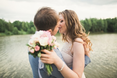 Happy wedding couple hugging and smiling each other on the background lake, forest.の写真素材