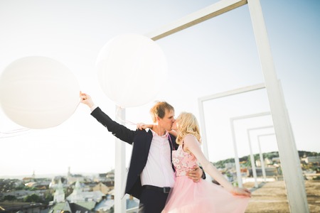 Pretty sunny outdoor portrait of young stylish couple while kissing on the roof with city view.の写真素材