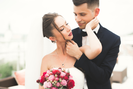 Beautiful couple, bride and groom posing on balcony with backgrounf of old city.の写真素材