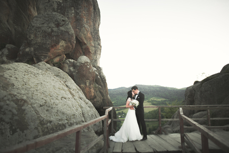 Happy wedding couple kissing and hugging near a high cliff.の写真素材