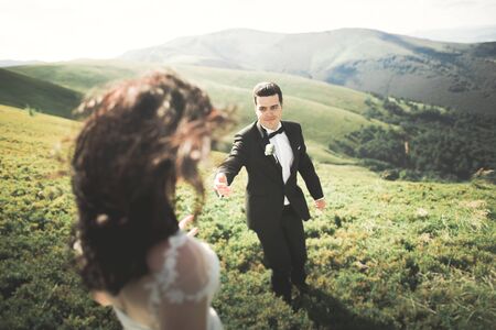 Beautiful gorgeous bride posing to groom and having fun, luxury ceremony at mountains with amazing view, space for text, wedding couple.の写真素材