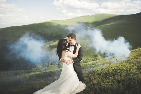Beautifull wedding couple kissing and embracing near mountain with perfect view.の写真素材