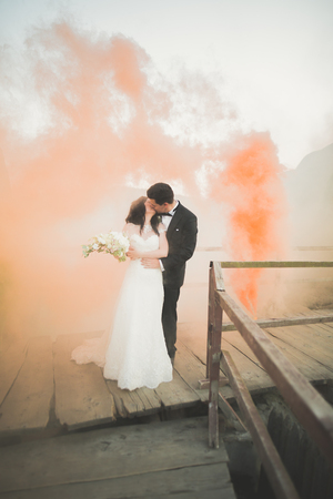 Wedding couple posing near rocks with colored smoke behind them.の写真素材