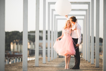 Pretty sunny outdoor portrait of young stylish couple while kissing on the roof with city view.の写真素材