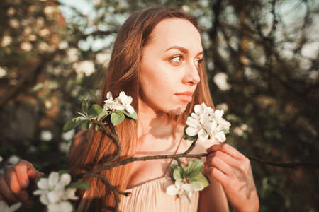 Young beautiful girl in a long dress and a wreath of flowers in the garden of lilac bush.の写真素材