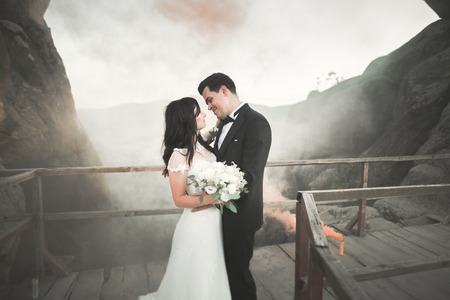 Happy wedding couple kissing and hugging near a high cliff.の写真素材
