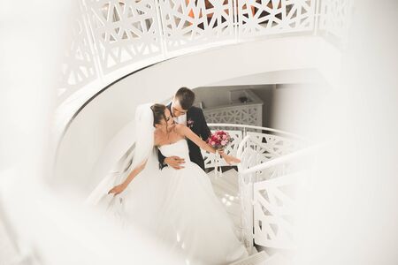 Lovely happy wedding couple, bride with long white dress posing in beautiful city.の写真素材