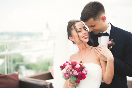 Beautiful couple, bride and groom posing on balcony with backgrounf of old city.の写真素材