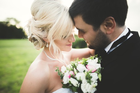 Wedding, Beautiful Romantic Bride and Groom Kissing and Embracing at Sunset.の写真素材
