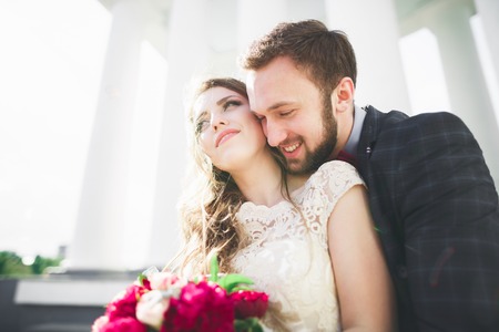 Beautiful couple, bride and groom posing near big white column.の写真素材