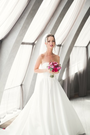 Beautiful bride with wedding bouquet posing in old city.の写真素材