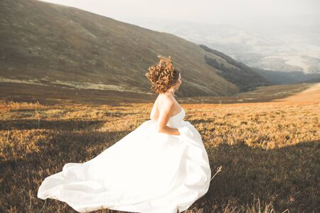 Happy beautiful young bride outside on a summer meadow at the sunsetの写真素材