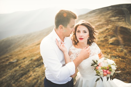 Happy wedding couple posing over beautiful landscape in the mountainsの写真素材