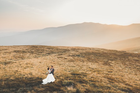 Happy beautiful wedding couple bride and groom at wedding day outdoors on the mountains rock. Happy marriage couple outdoors on nature, soft sunny lightsの写真素材