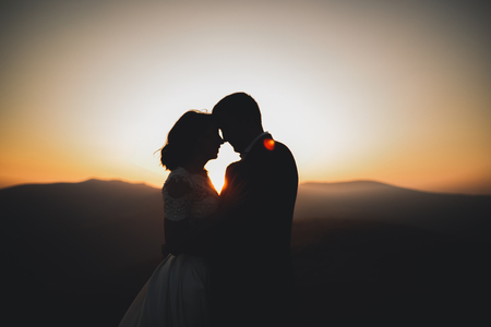 Happy beautiful wedding couple bride and groom at wedding day outdoors on the mountains rock. Happy marriage couple outdoors on nature, soft sunny lightsの写真素材