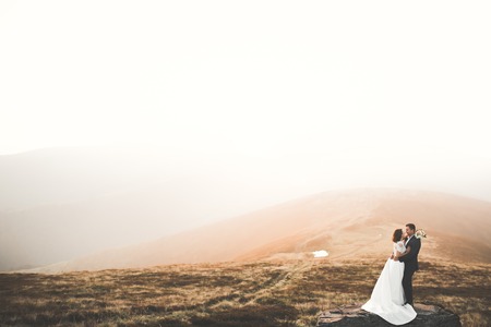 Beautifull wedding couple kissing and embracing near mountain with perfect viewの写真素材
