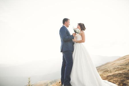 Happy wedding couple posing over beautiful landscape in the mountainsの写真素材