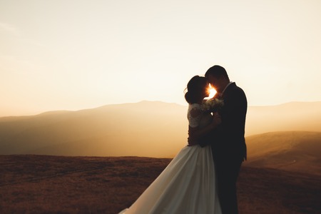 Happy beautiful wedding couple bride and groom at wedding day outdoors on the mountains rock. Happy marriage couple outdoors on nature, soft sunny lightsの写真素材
