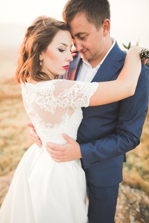Happy beautiful wedding couple bride and groom at wedding day outdoors on the mountains rock. Happy marriage couple outdoors on nature, soft sunny lightsの写真素材