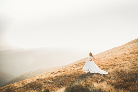Happy beautiful young bride outside on a summer meadow at the sunsetの写真素材