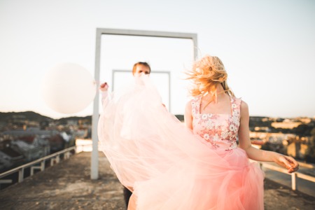 Fashion lovely beautiful couple posing on roof with city background. Young man and sensual blonde outdoor. Lifestyle..の写真素材
