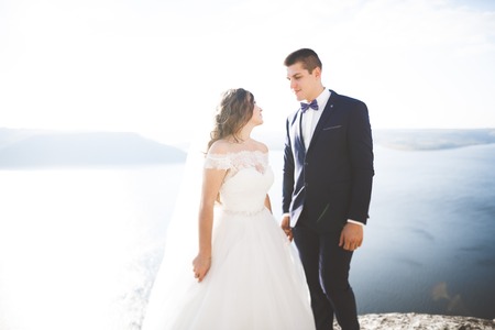 Wedding couple kissing and hugging on rocks near blue seaの写真素材